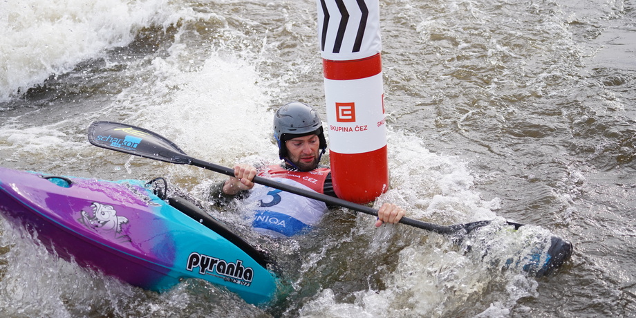Kanufahrer kämpft in der Strömung gegen eine Boje, Wasser spritzt um ihn herum.