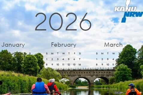 Vier Kajakfahrer paddeln auf einem ruhigen Gewässer unter einem Brückenbogen, umgeben von grüner Natur.