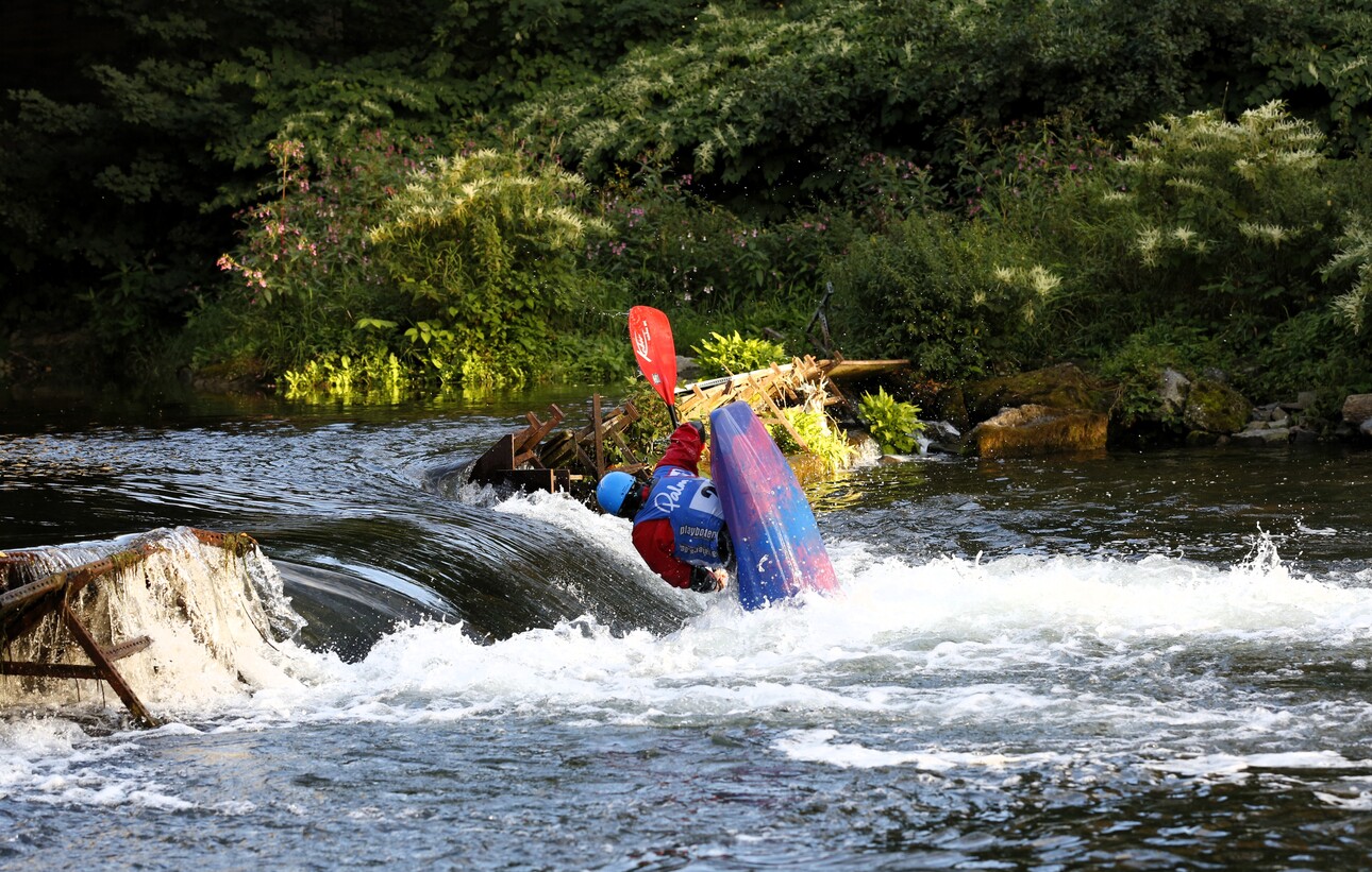 Kajakfahrer im Wasser, der bei einem Hindernis in einer unruhigen Strömung eine Wendung vollzieht.