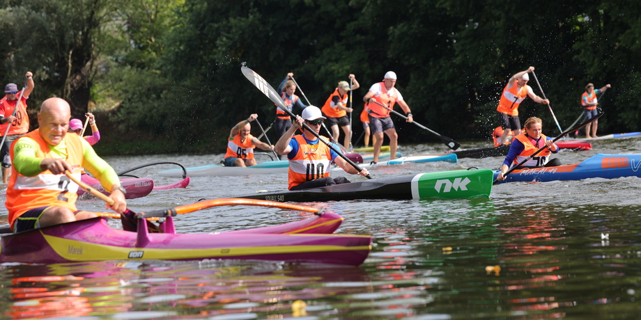 Ruderregatta mit mehreren Teilnehmern in leuchtenden Westen auf einem Gewässer, verschiedene Ruderboote in Aktion.