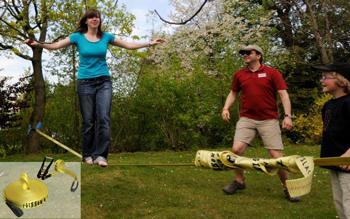 Frau balanciert auf einer Slackline im Freien, während zwei Zuschauer sie anfeuern.